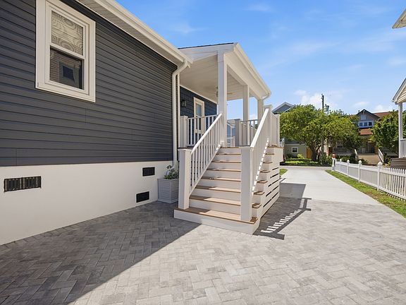 Driveway and front patio with stairs leading to the main entrance.