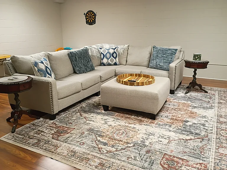 The family room features a comfy sectional sofa and an ottoman for added comfort.