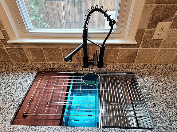 9-Inch deep undermount stainless steel kitchen sink with a pot-filler and separate sprayer that lights up and changes light color based on water temperature. The sink has built-in drying racks for produce and a built-in cutting board (all can be romoved).