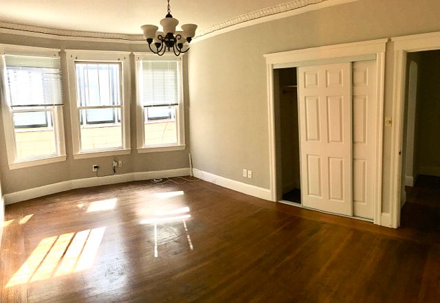 Bedroom with sliding door closet. Window eastward overlooks small yard between property and neighboring building.