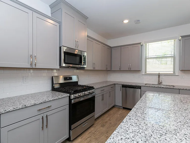 Sleek kitchen with gray cabinetry and granite countertops.