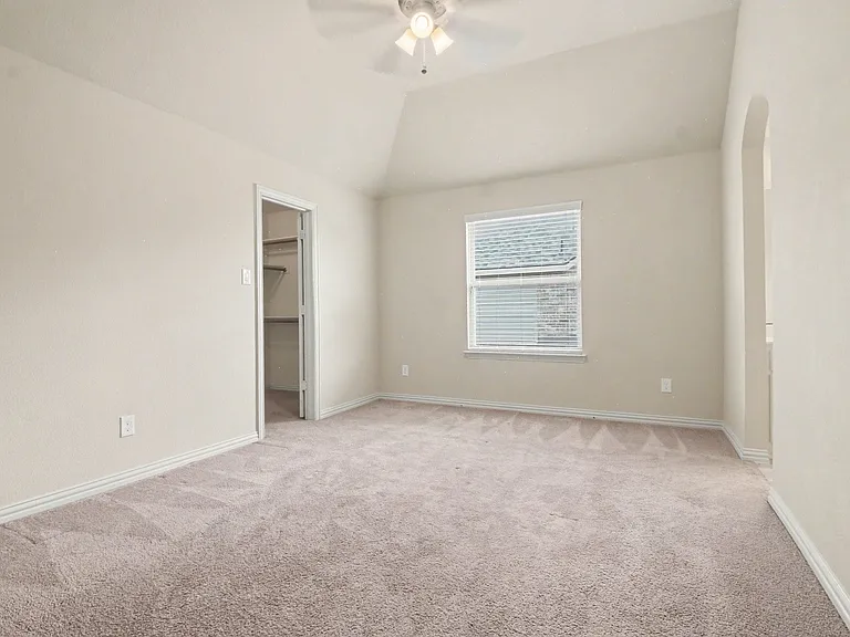 Carpeted room featuring a vaulted ceiling and a ceiling fan