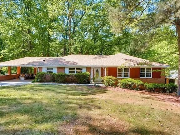 Front of the home before we removed the bushes and put new siding where the red-painted paneling is now.