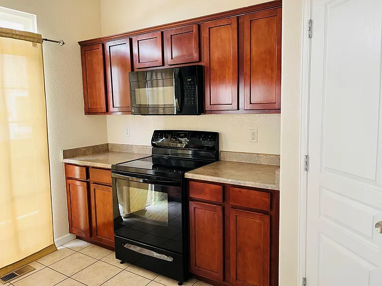 Kitchen is equipped with an ice and water filtration system refrigerator, dishwasher, stove with an overhead microwave, beautiful cherry finish cabinets, and a small balcony.