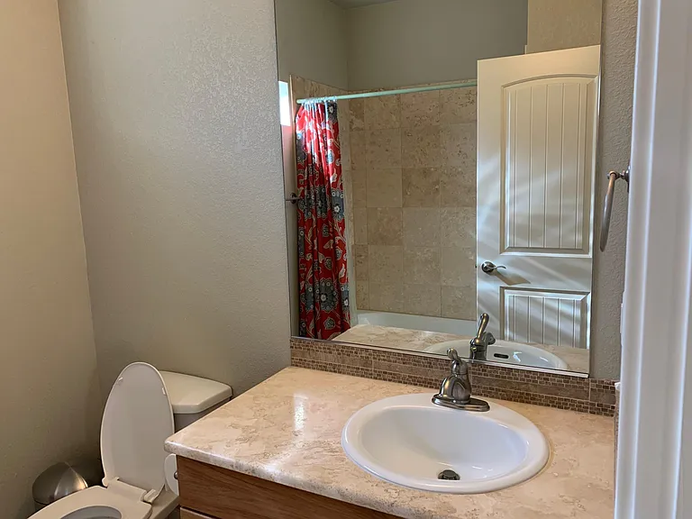 Guest bathroom with full bath. Travertine, vanity and travertine tile in shower