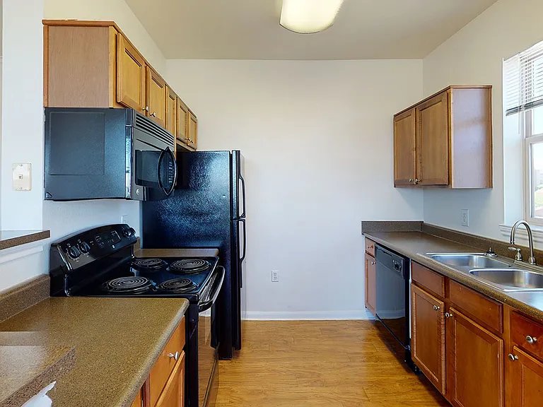 Apartment kitchen with wood-style flooring.