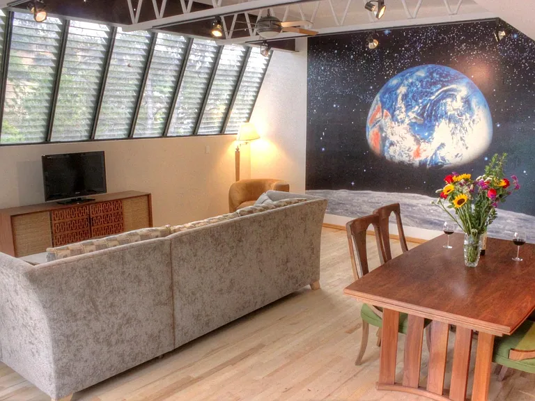 TV, Console, couch with chaise under east facing bank of windows with hillside views including Hollywood Sign.
