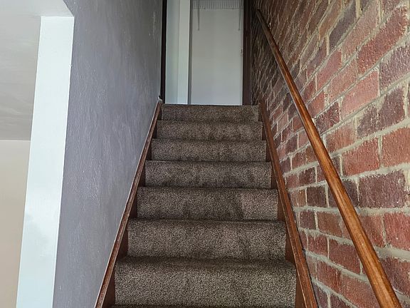 The newly carpeted staircase leads to the upstairs bedroom and full bathroom.
