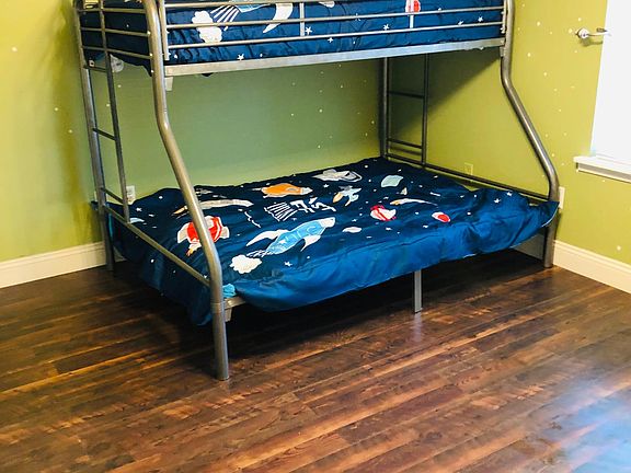 Kits room with a twin bunk and full size bunk, a dresser and a book shelf stocked with books.