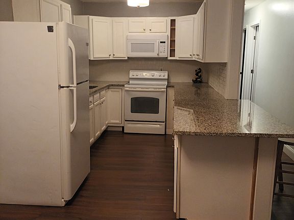 Galley kitchen with granite countertops, white backsplash