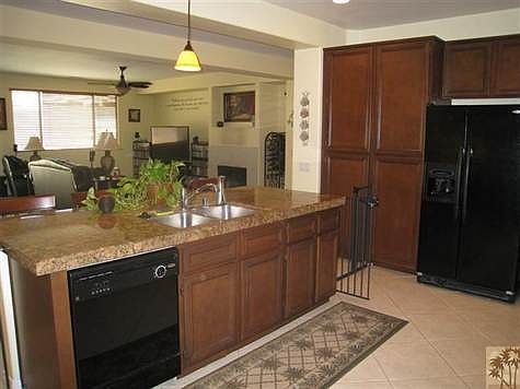 Open great room floor plan with black appliances and tile granite counters.