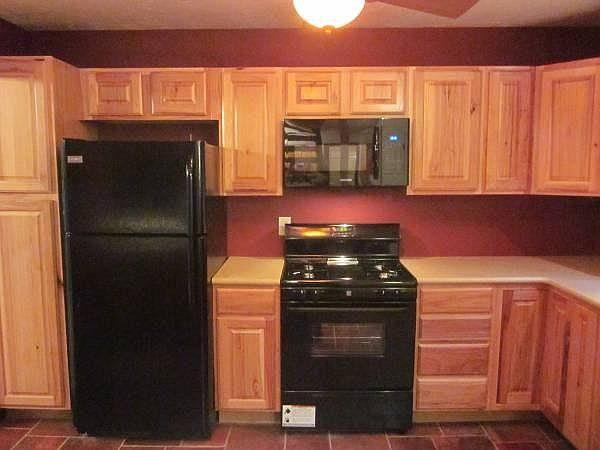 Fully renovated kitchen with hickory cabinets, solid surface countertop, & gas stove