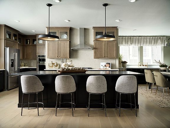 A modern and spacious kitchen with a large island, wooden cabinets, and pendant lights, featuring a