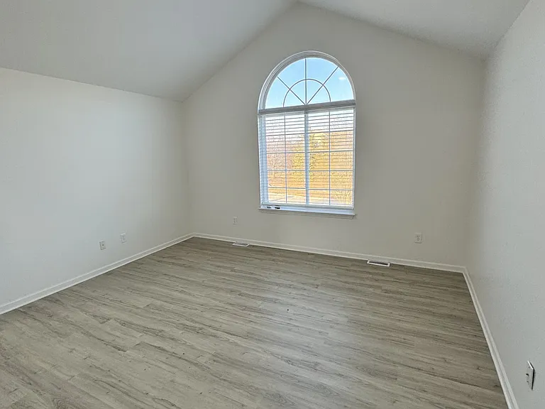 mid level primary suite with cathedral ceiling, circletop window, LVT floors and ceiling fan