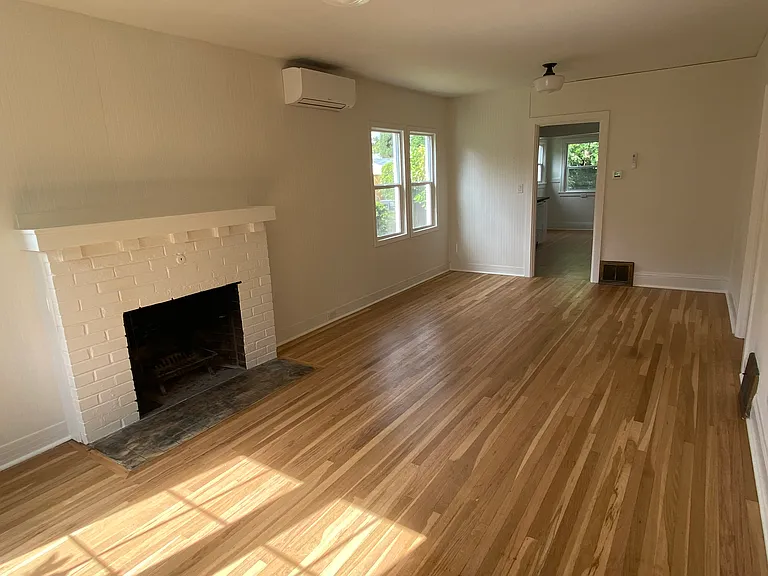 Living room with wood burning fireplace and mini split with air conditioning and heat