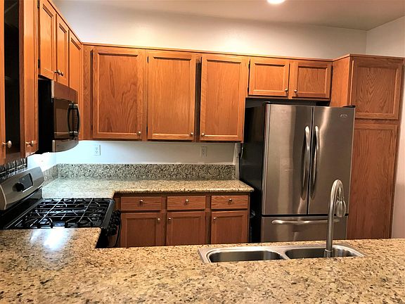 Granite kitchen counter top with gas stove, refrigerator, and dishwasher.