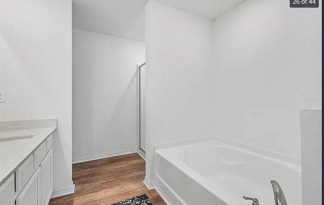Functional bath area with a soaking tub, long vanity with ample storage, and durable wood-look flooring for easy upkeep. - Ryken Ln