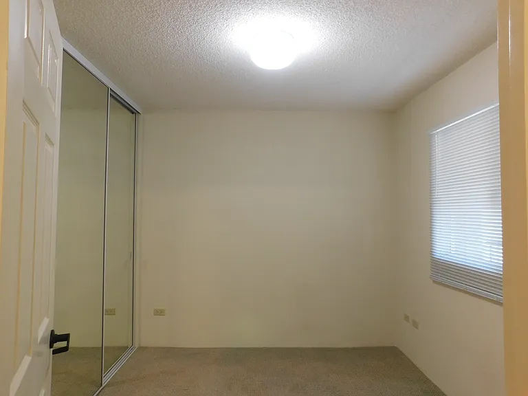 Guest bedroom with mirrored closet doors.
