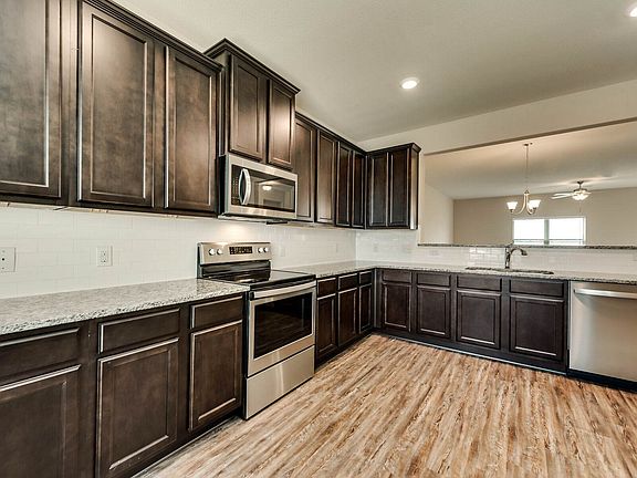 The kitchen showcases granite countertops, stunnign wood cabinetry and a gorgeous backsplash.