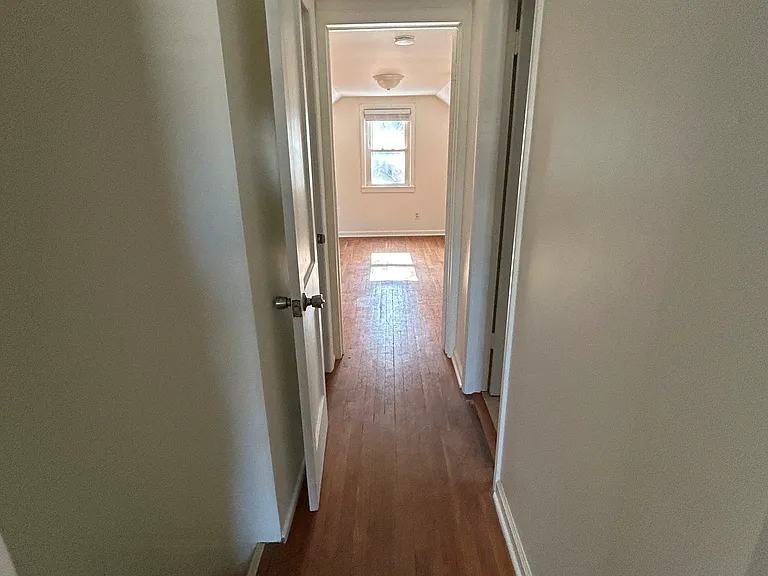 Upstairs hallway from small bedroom. Other bedroom straight ahead, large closet on the left, and bathroom on the right.