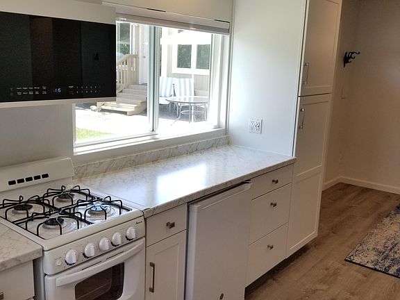 Pantry, gas range, under counter refrigerator and microwave oven with external exhausting vent and light.