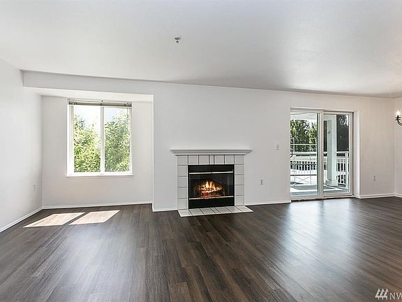 Spacious living room with bright windows and a cozy wood-burning fireplace.