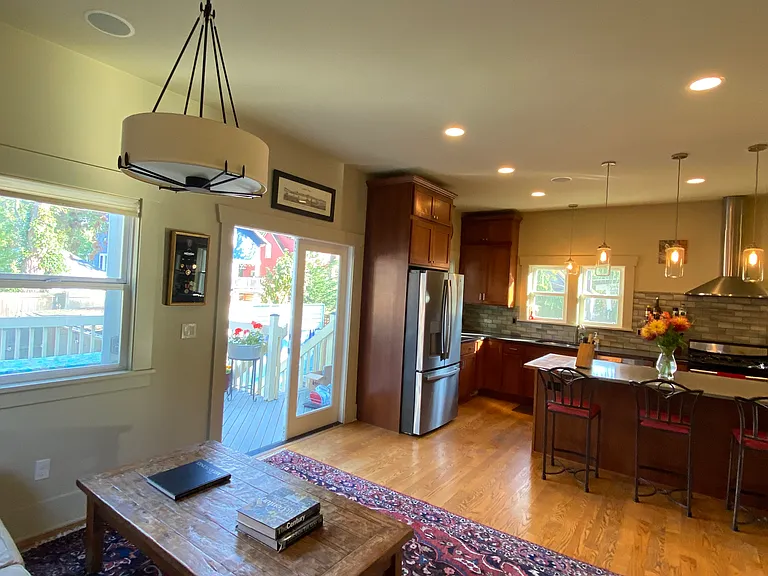 View of French doors to deck with BBQ, stairs down to hot tub and yard with fire pit