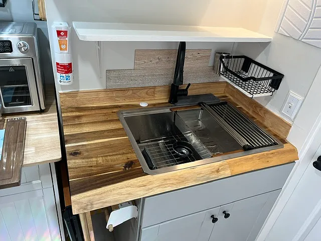 Newly installed kitchen cabinet with wood counter top, sink and faucet.