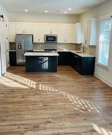 Open Den to Kitchen Floor Plan with Island and stainless steel appliances
