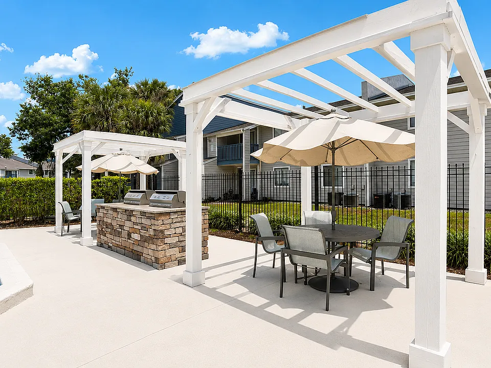 Inviting outdoor barbecue area with stylish pergola, elegant dining set, and modern grills beside a serene pool.