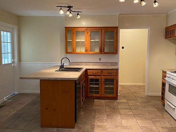 Country kitchen looking into small room that could be used as an open door pantry. This leads to the small bathroom with tile wall