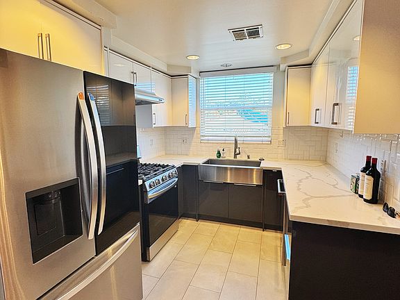 The kitchen features newer appliances, including a refrigerator, range, oven, and dishwasher, along with a marble countertop.