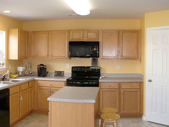 The kitchen features maple cabinets, black appliances, and pantry