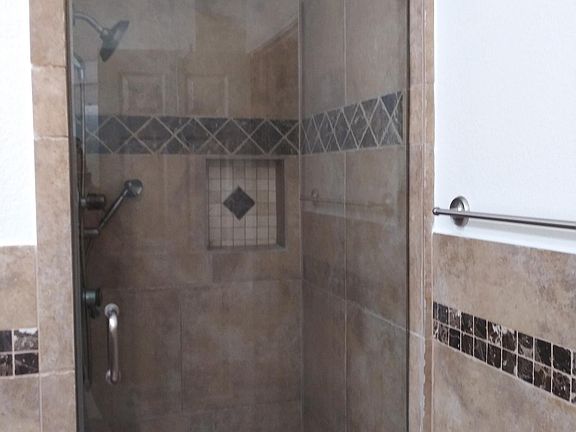 Master Shower with frame-less shower door and hand-held shower.