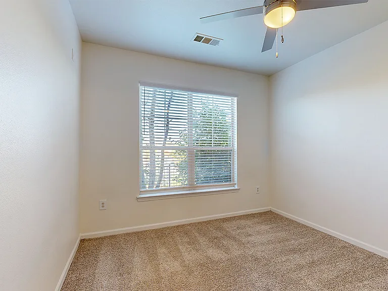 Spacious apartment bedroom with plush carpet flooring.