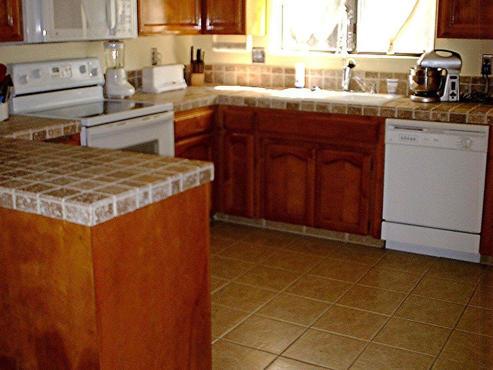 Newly tiled floor and counter tops with new appliances and paint in kitchen