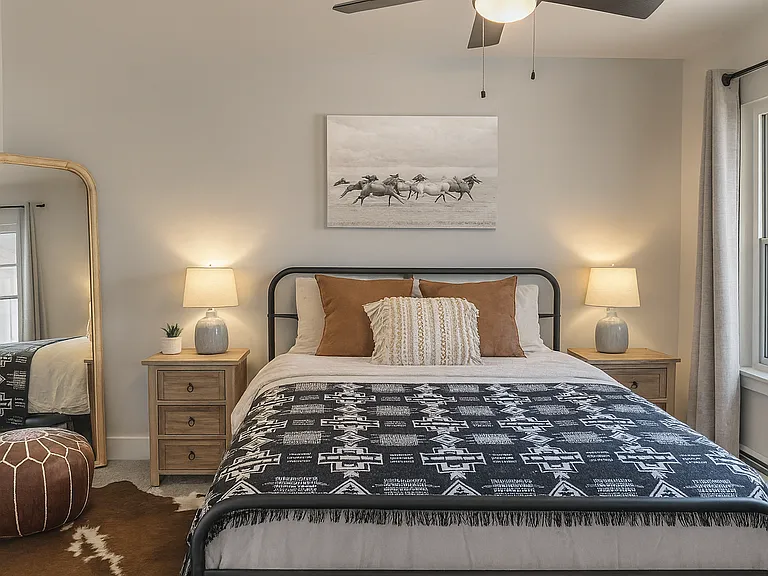 Rest easy in the spacious primary bedroom featuring a queen bed, plush bedding, and calming natural textures.
