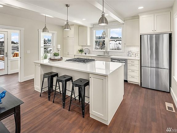 Bright white cabinetry, stainless appliances, gas cooktop and quartz countertops modernize the home, while the kitchen and sunroom placement reflect the authentic design of the home.