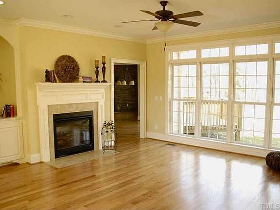 Living room is filled with light, a gas log fireplace and a built-in cabinet. 