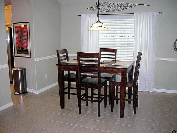 The formal dining room has a tile floor and contemporary light fixture.