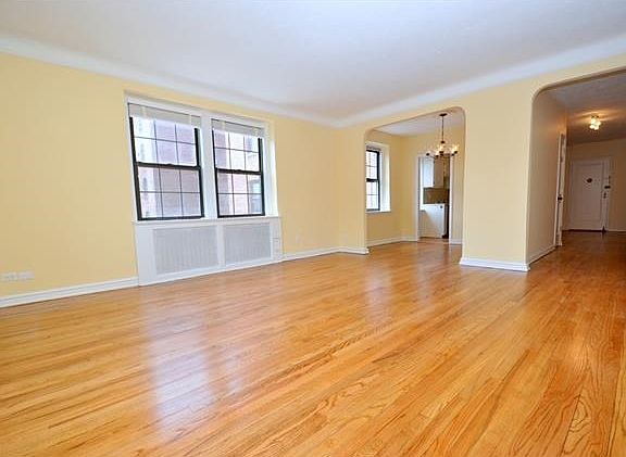 The large, sunny, corner living room has eastern and southern exposures and an arched opening to a s