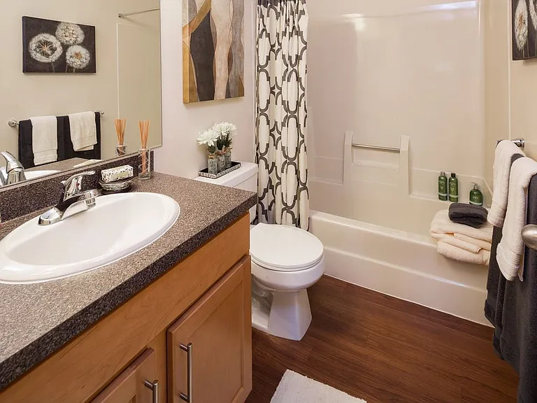 Classic Package bathroom with black speckled laminate countertops, maple cabinetry and hard surface flooring