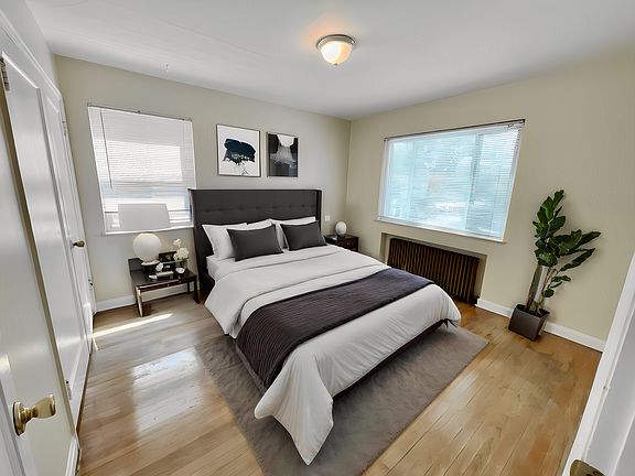 Bright and inviting bedroom with modern decor, featuring a plush bed, elegant side tables, cozy lighting, and large windows providing natural light.