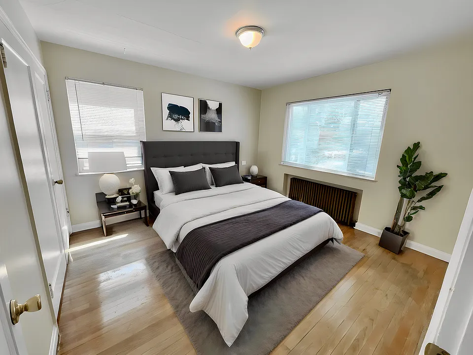 Bright and inviting bedroom with modern decor, featuring a plush bed, elegant side tables, cozy lighting, and large windows providing natural light.