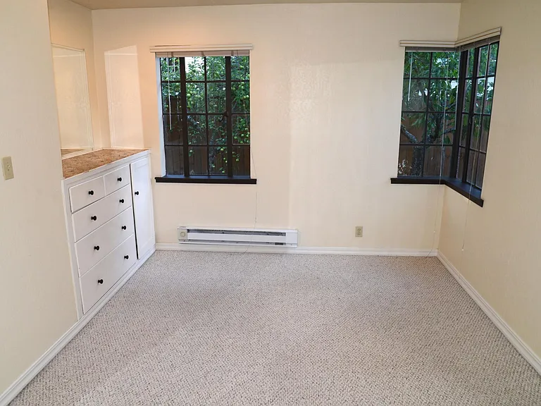 Master bedroom with built-in bureau, corner wrap-around window. Apple and cherry trees are outside the windows.