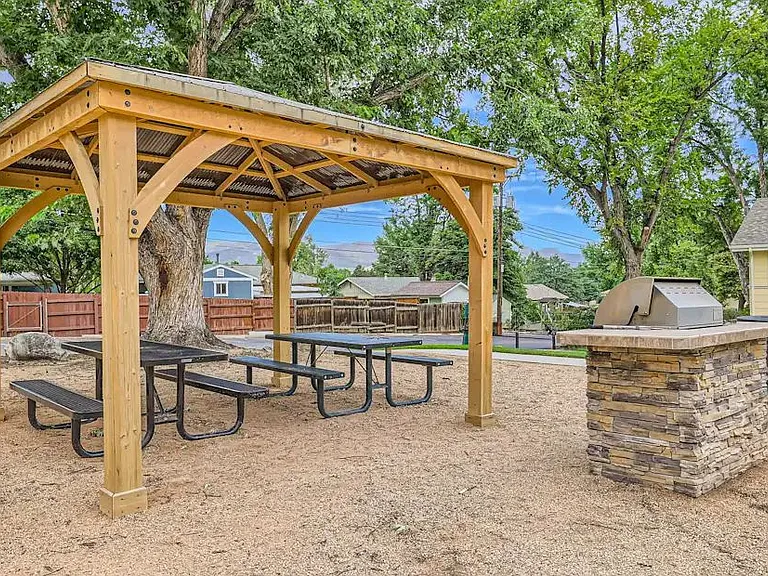 Pergola covering two picnic tables and a grill on the side