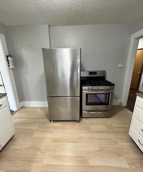 Full size fridge with freezer. To the left is the exterior entrance, to the right is the central hallway.