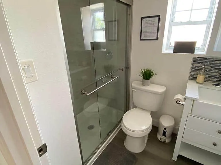 Spotless bathroom featuring a mirror, storage cabinet, shower, and toilet.