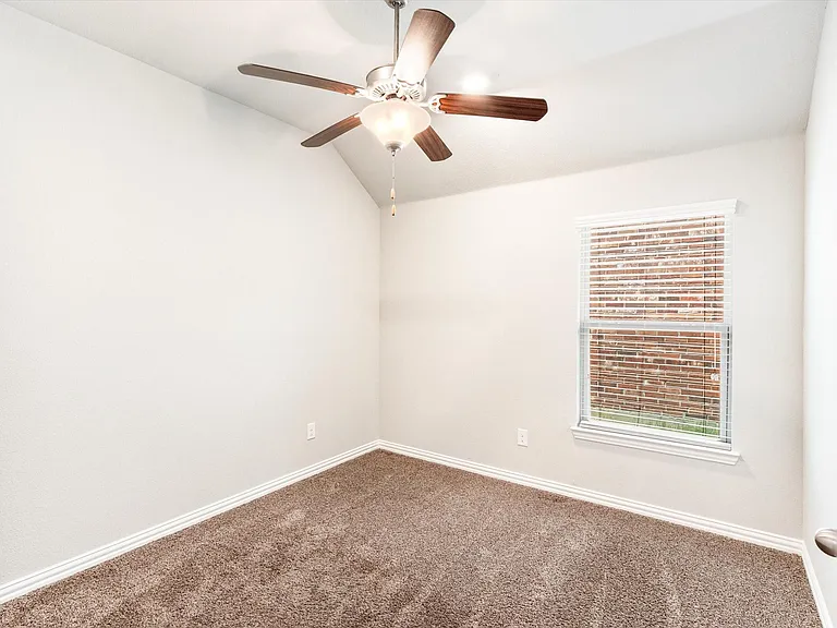 Vaulted ceiling bedroom with neutral-toned carpeting and a ceiling fan with integrated lighting