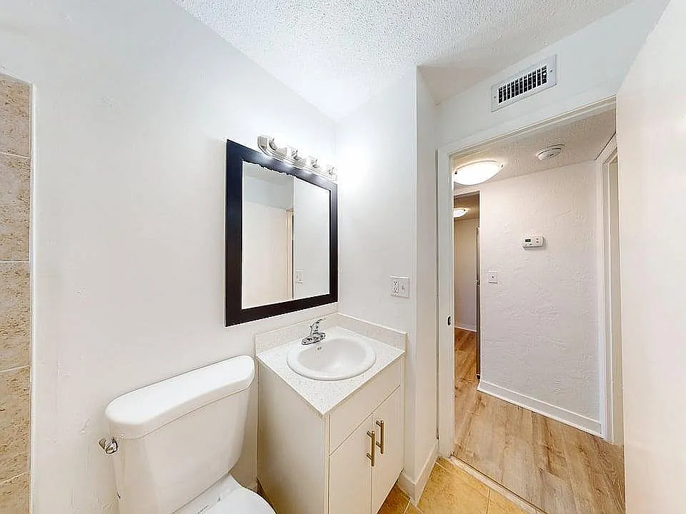 Bright, modern bathroom with elegant fixtures and a spacious layout, featuring a sleek countertop and warm lighting.